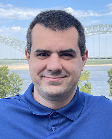 Portrait of Evan Boulanger - man wearing a blue shirt smiling at the camera