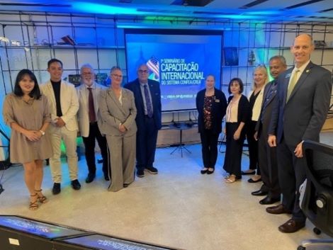 Ten people are in front of a screen facing the camera and smiling