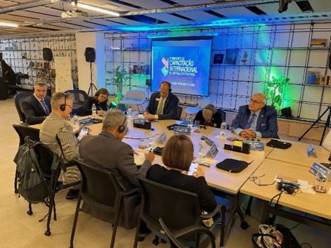 Eight people are sitting around a table with headphones on listening to a presentation. 