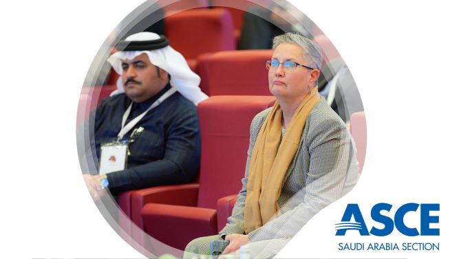 Two people sitting in an auditorium watching a presentation. 