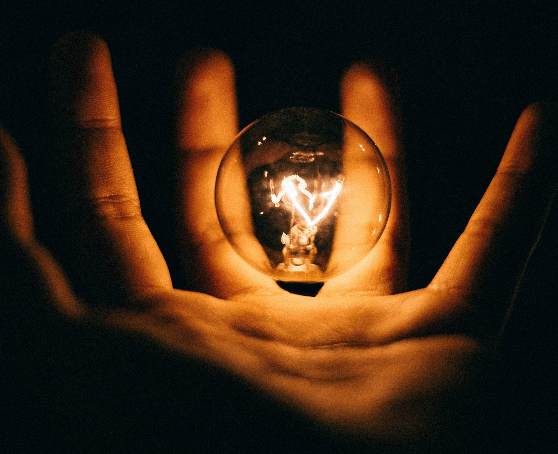 lit light bulb hovering over hand