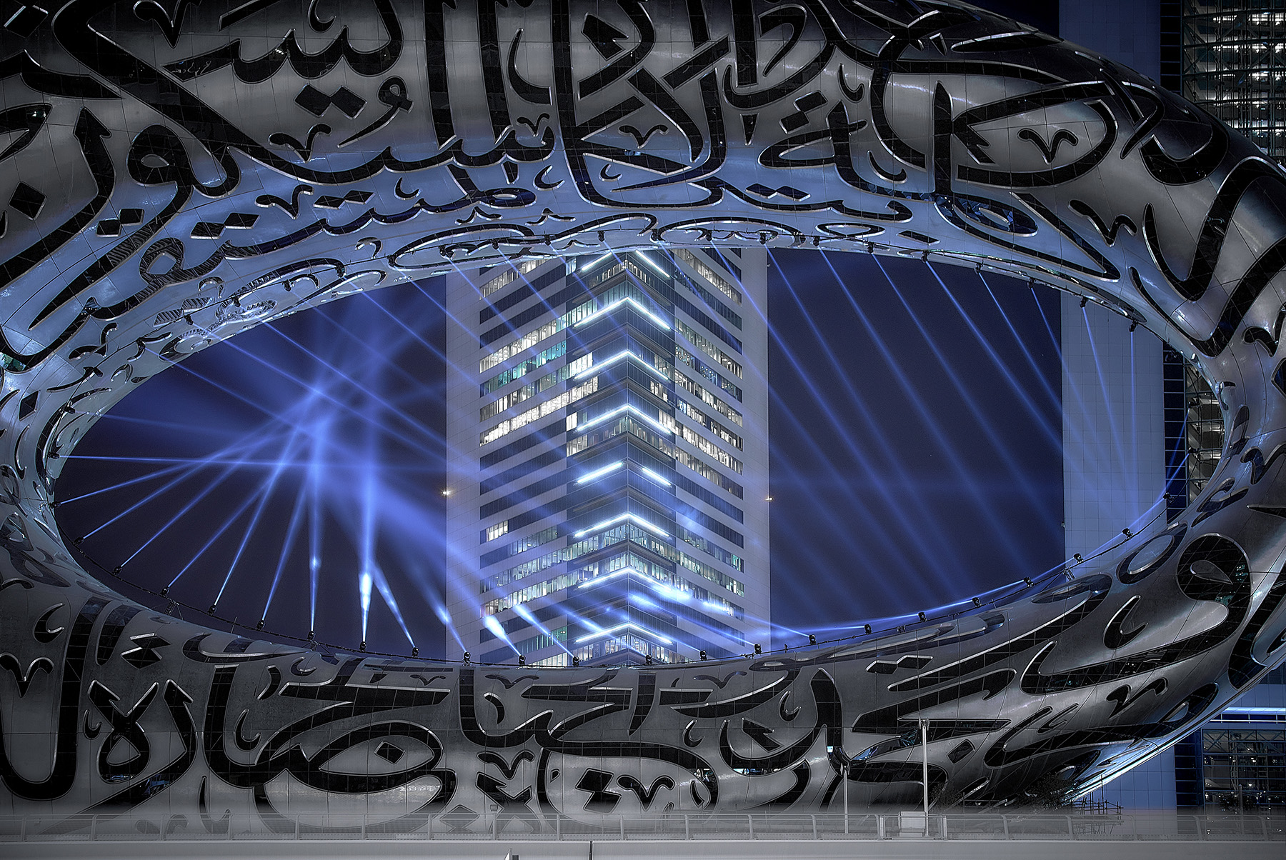 The void created by an elliptical structure. Lights are illuminating the facade and a building is seen in the background.