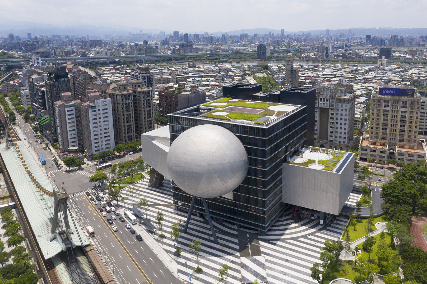 Four-sided building with different shapes projecting from it on three sides. 