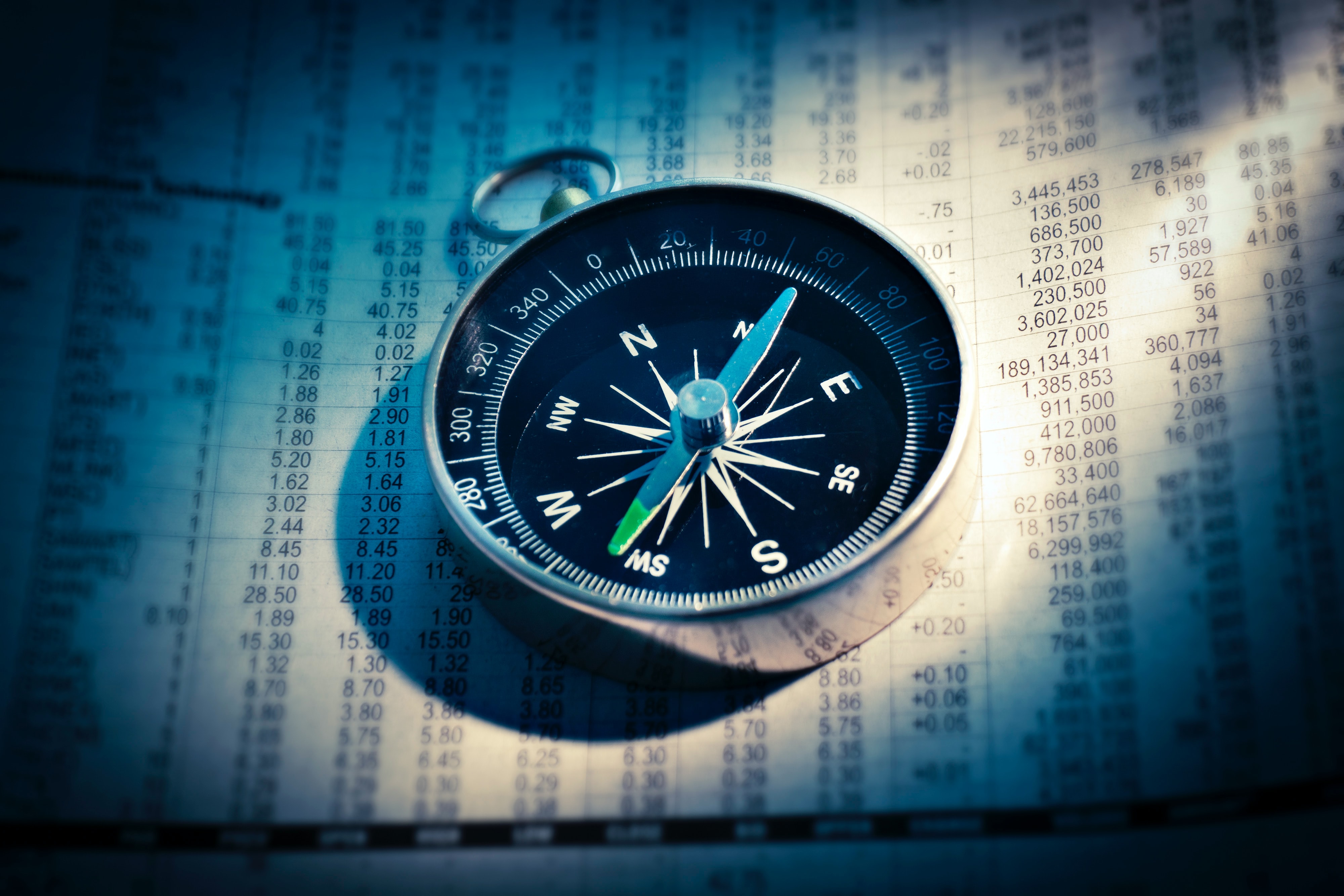 A compass sitting on top of a page of numbers.