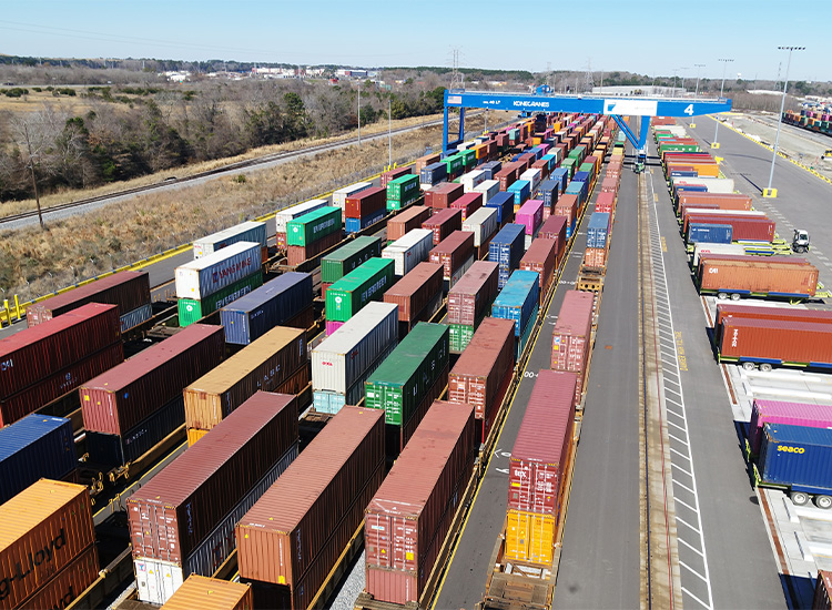 Multiple shipping containers in different colors sit in a shipping yard. 