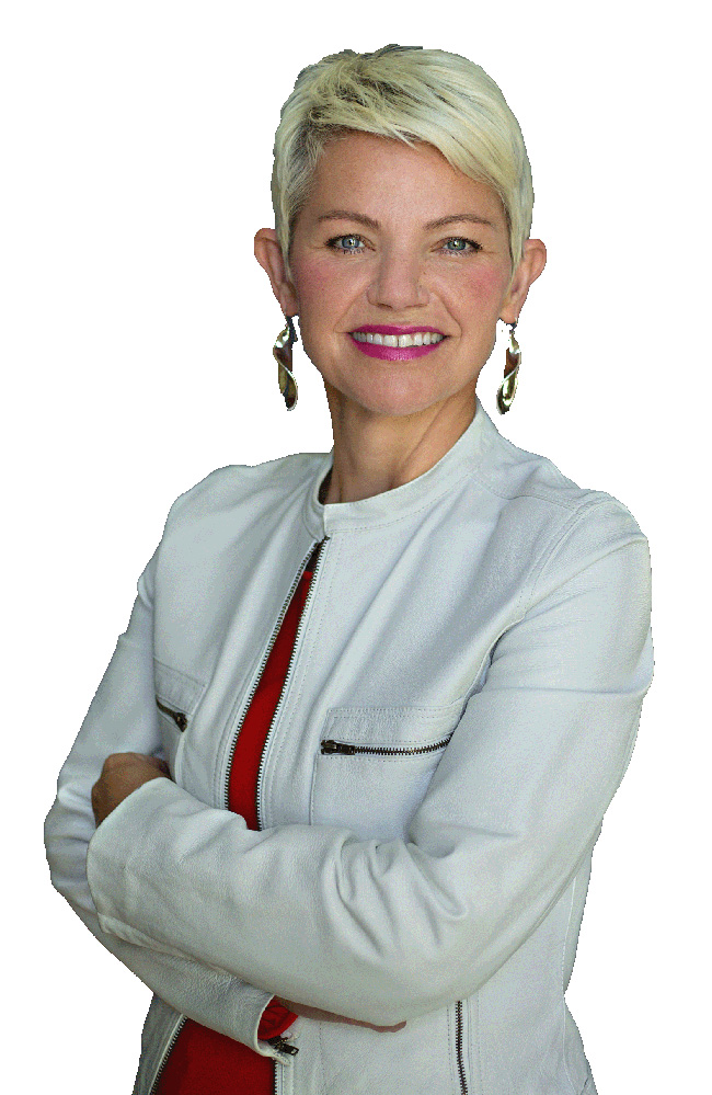 Woman with short blond hair wearing a white leather jacket and pink shirt smiles at the camera.