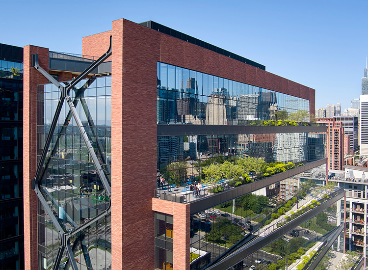 A large multistory, brick, glass, steel, and concrete structure is shown.