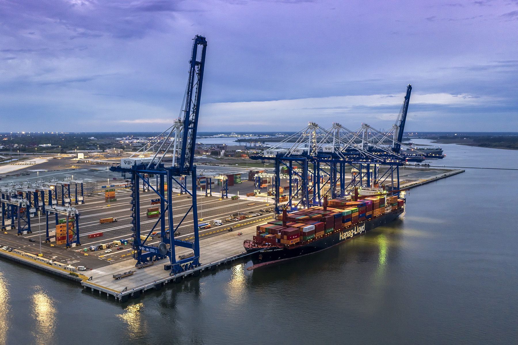 Image shows a water-based shipping terminal featuring a berth, container yard, and electric gantry cranes.