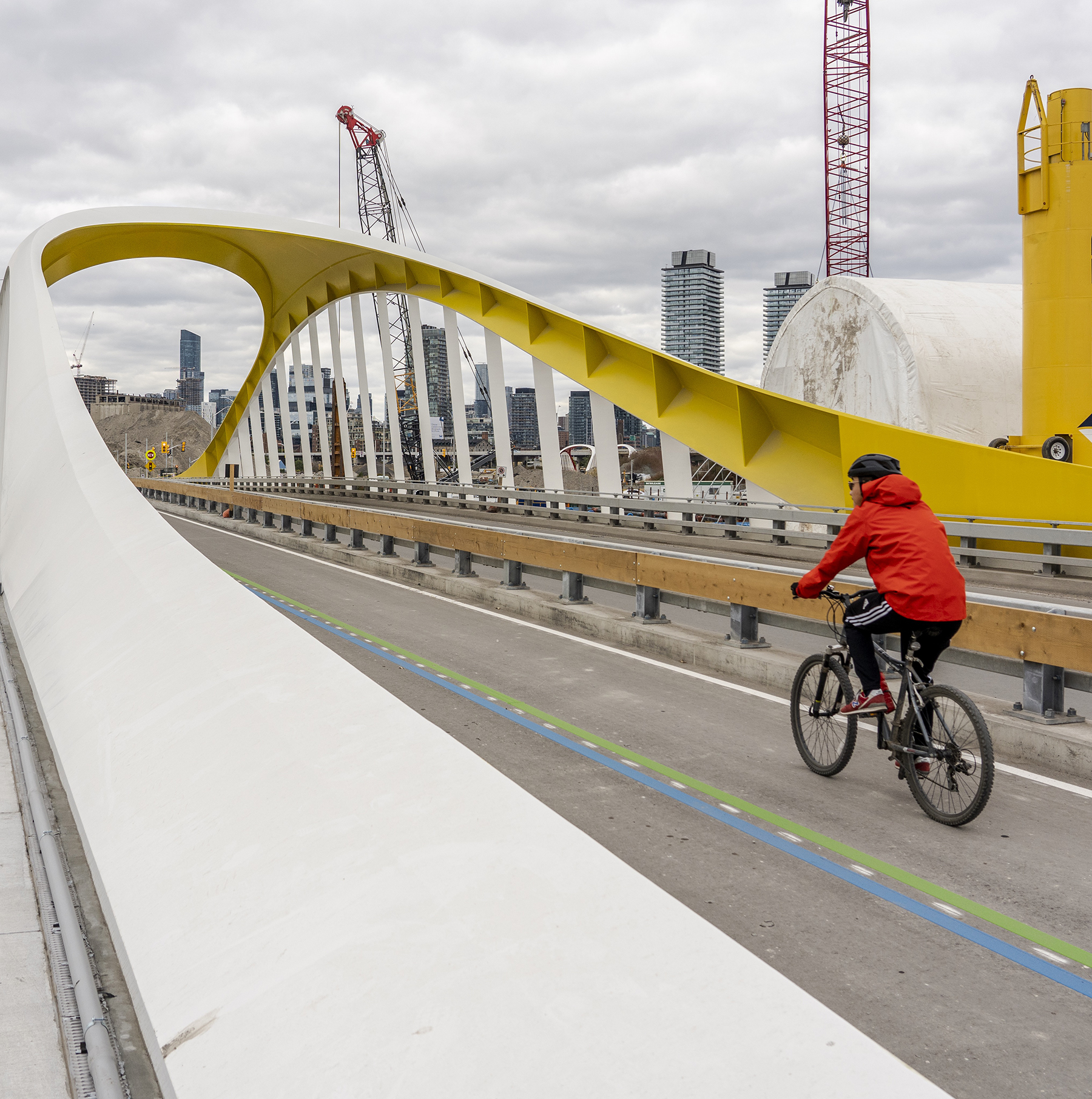 a cyclist crosses a bridge with the city skyline in the background