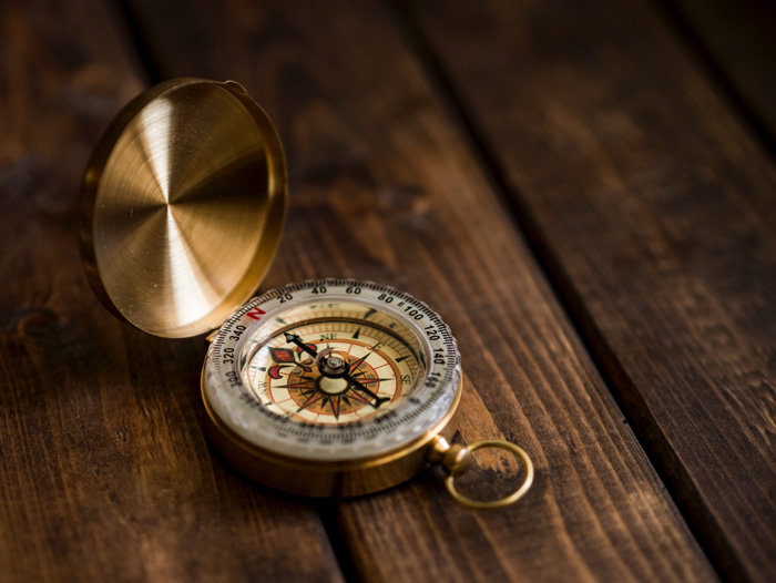 A golden compass rests on a hardwood floor, Credit: Aaron Burden